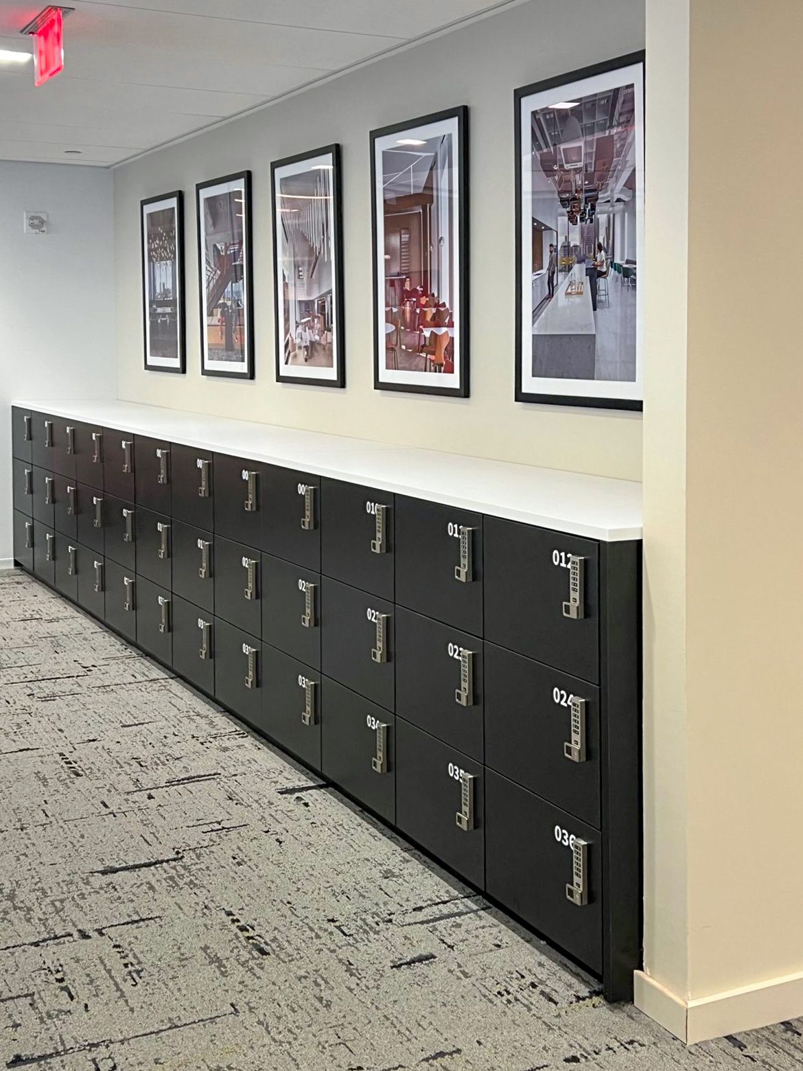 Charcoal low-profile lockers running along a corridor beneath an art wall