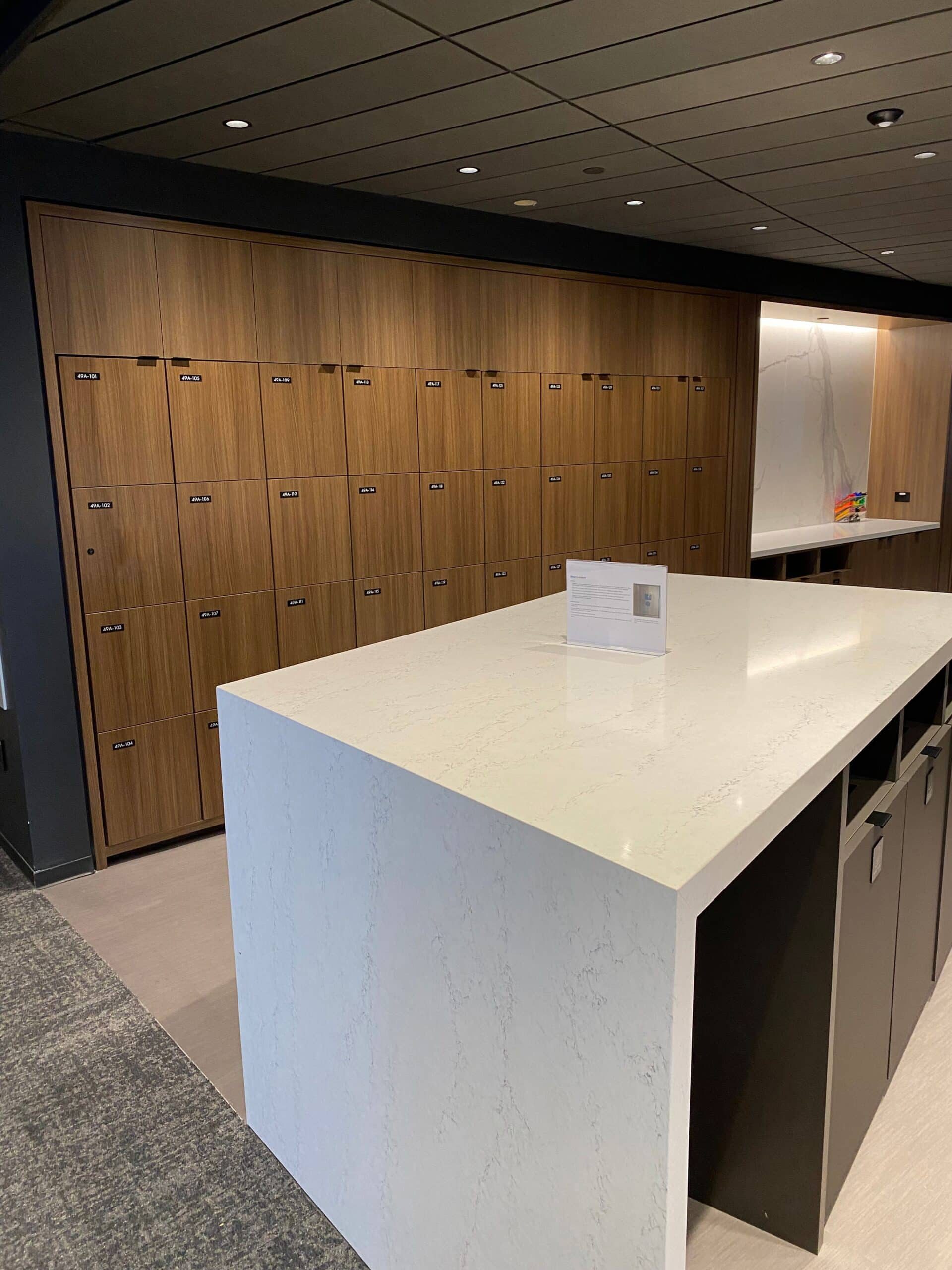 Dark walnut Arraya locker wall with quartz-top island in Manhattan corporate office