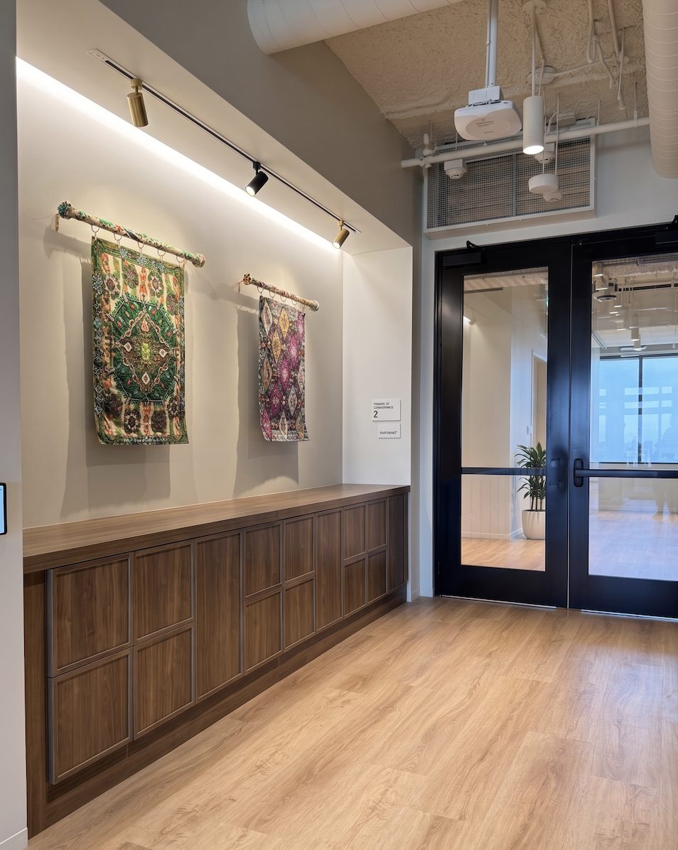 Dark walnut counter-height lockers in an NYC office lobby corridor with art