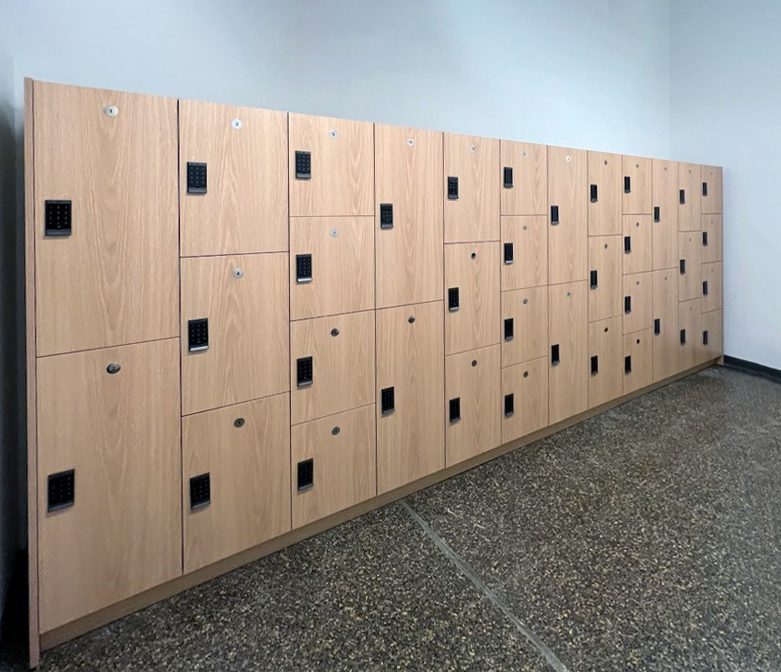 Light maple woodgrain 3-tier locker wall with black locks on terrazzo floor