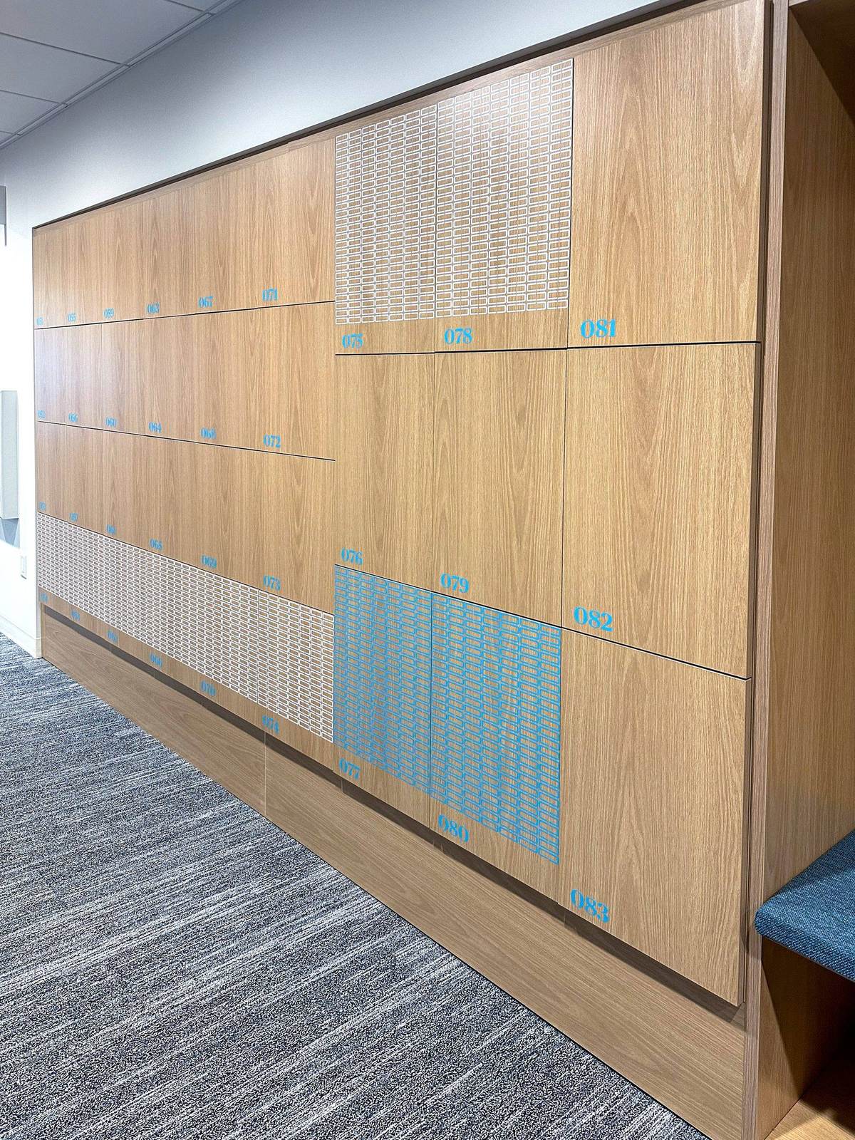 Chubb Chicago oak locker wall with cyan vinyl numbers and woven accent panels — enterprise corporate installation