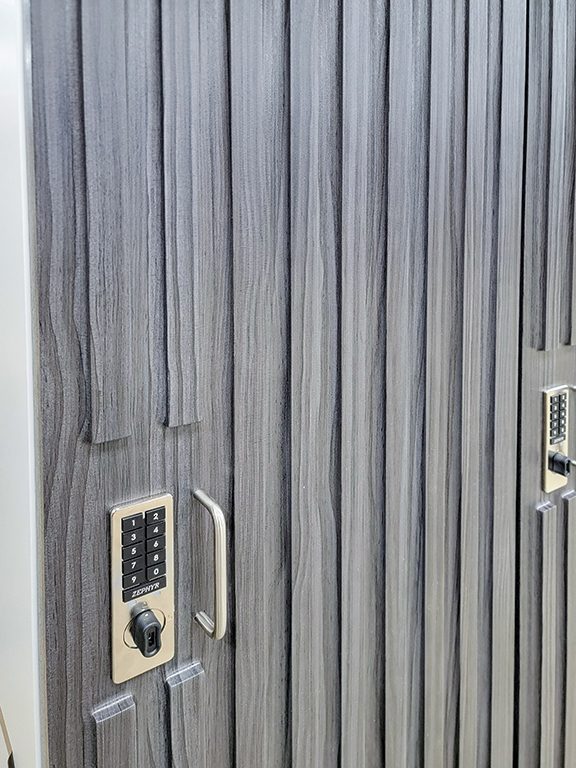 Close-up of reeded fluted gray laminate locker door with pin keypad lock