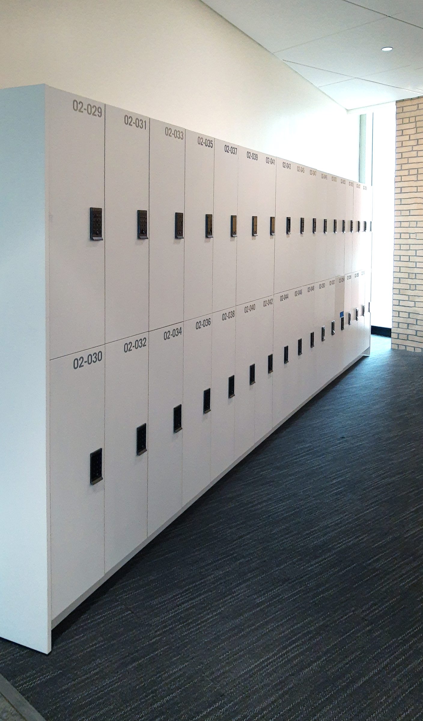 White 2-tier laminate office lockers in a long campus corridor