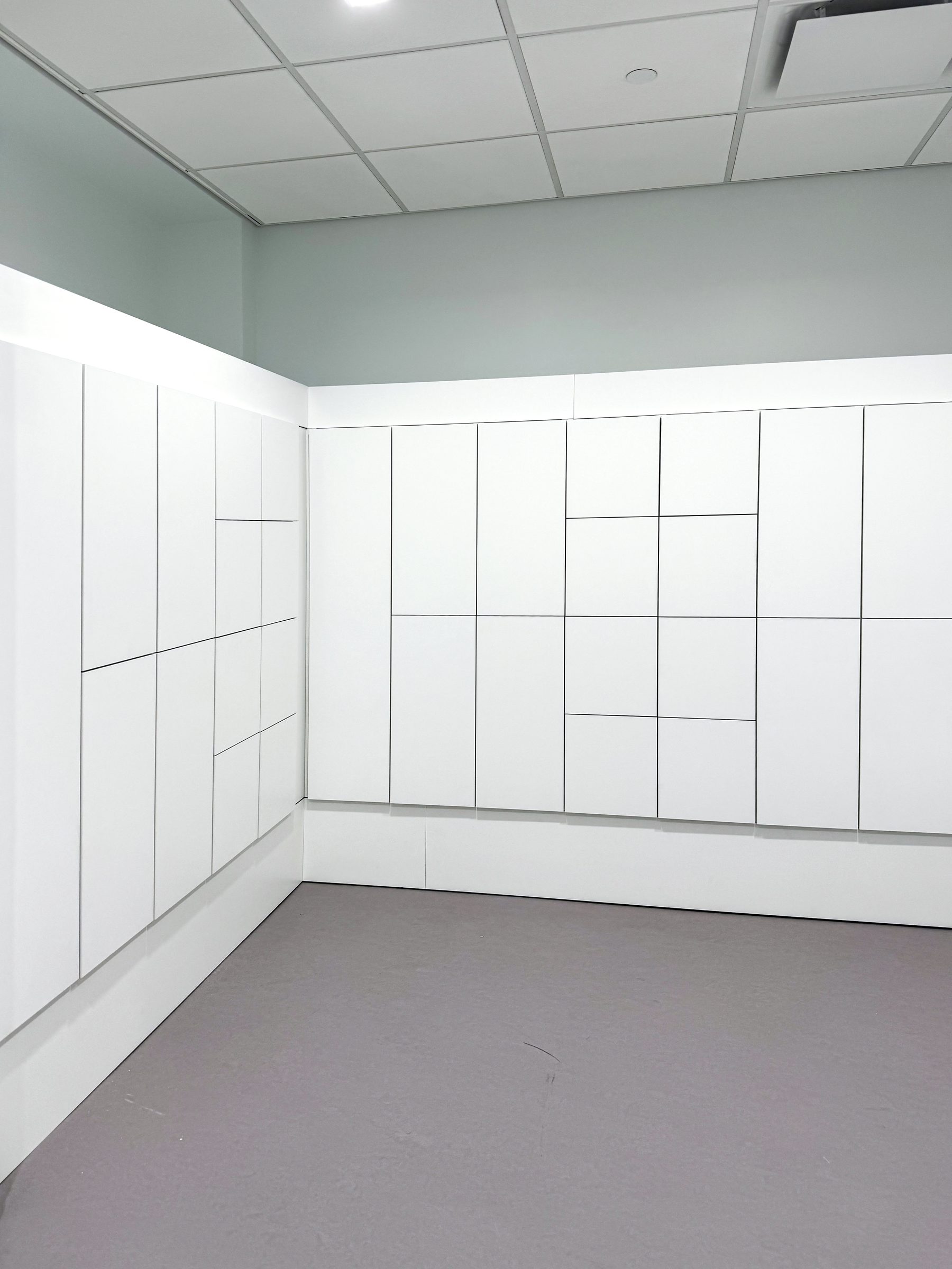 White floor-to-ceiling locker room with lockers on two walls — NYC media company
