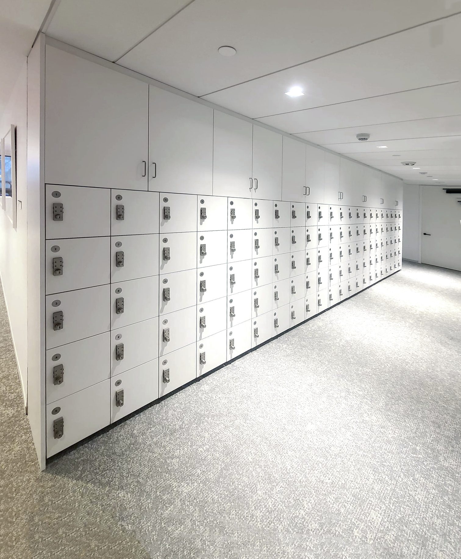 White laminate wall lockers in a lit enterprise corridor