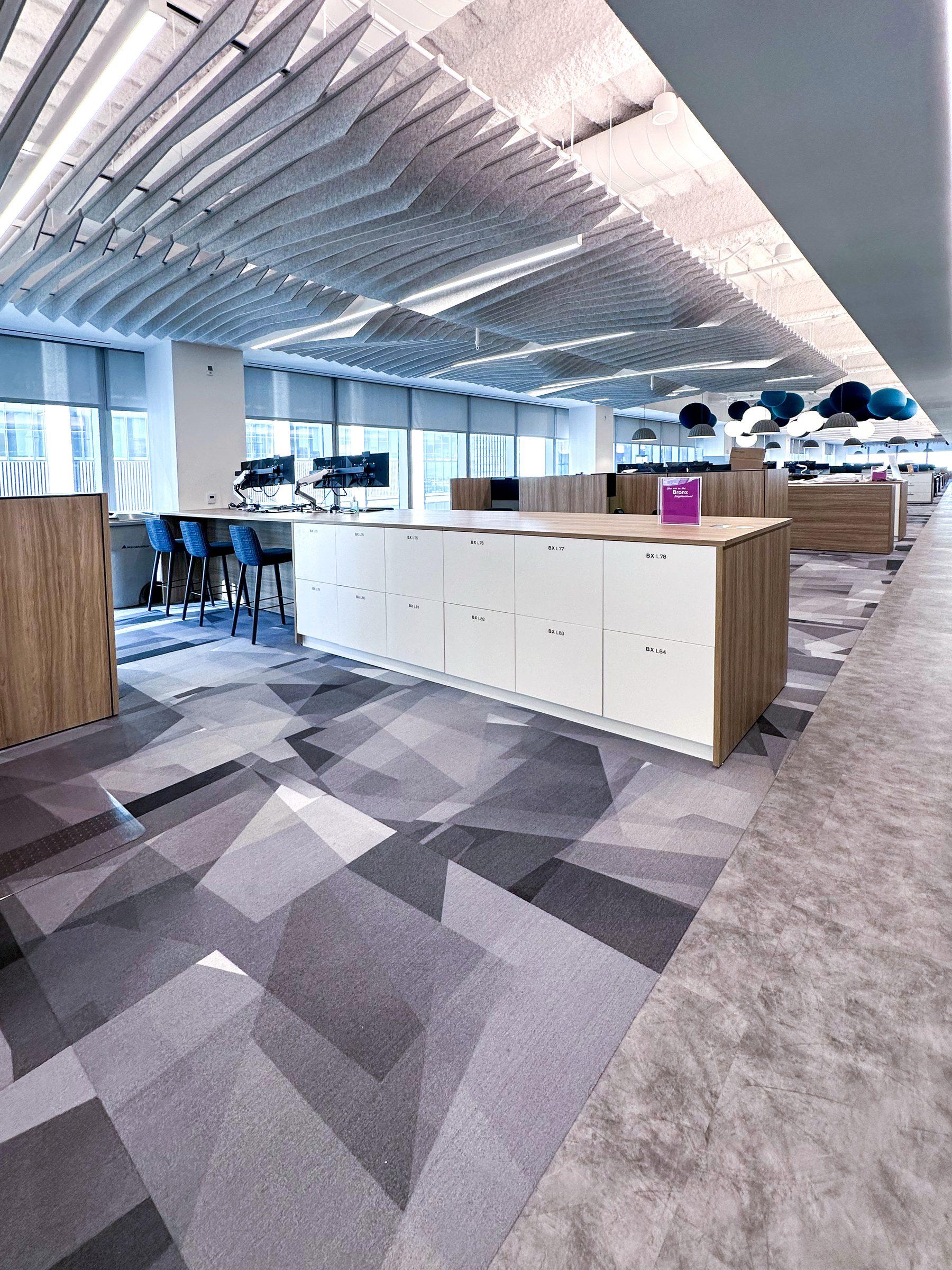 White counter-height end-cap locker island with wood top — open-plan corporate office