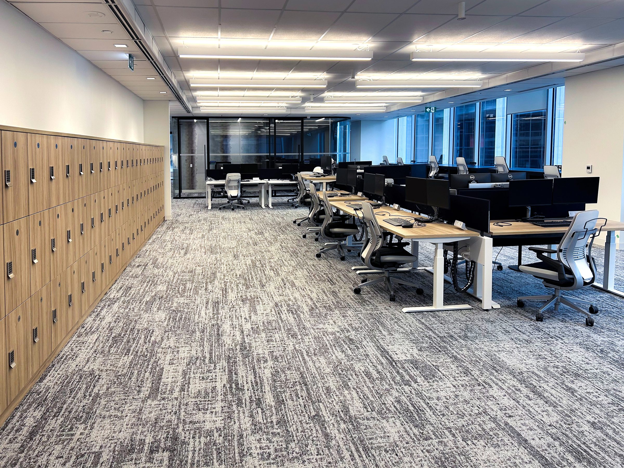 Woodgrain wall lockers alongside open-plan office workstations